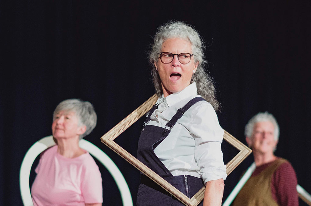 women performing with frames around their necks.