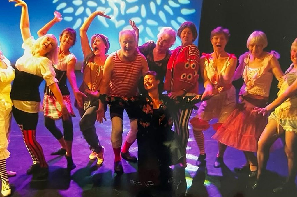 group of older people posing for a picture on stage in costumes. 
