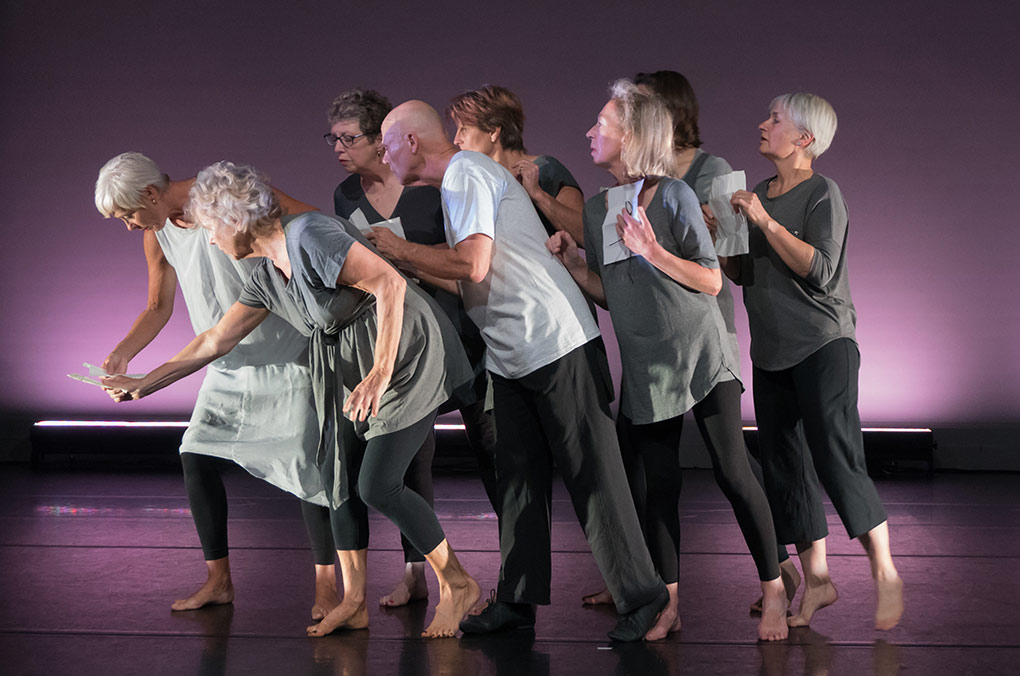 group of older people posing for a picture on stage in costumes. 